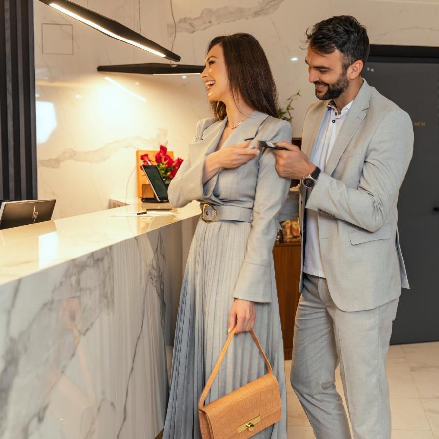 Hotel Pupin โนวีซาด ภายนอก รูปภาพ A man helping a woman with her coat